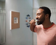 man-brushing-teeth-orange-shirt.jpeg